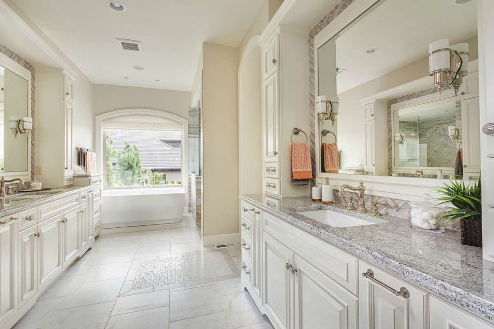 Example of a large classic master marble floor and white floor bathroom design in St Louis with raised-panel cabinets, white cabinets, beige walls, an undermount sink, quartz countertops and a hinged shower door
