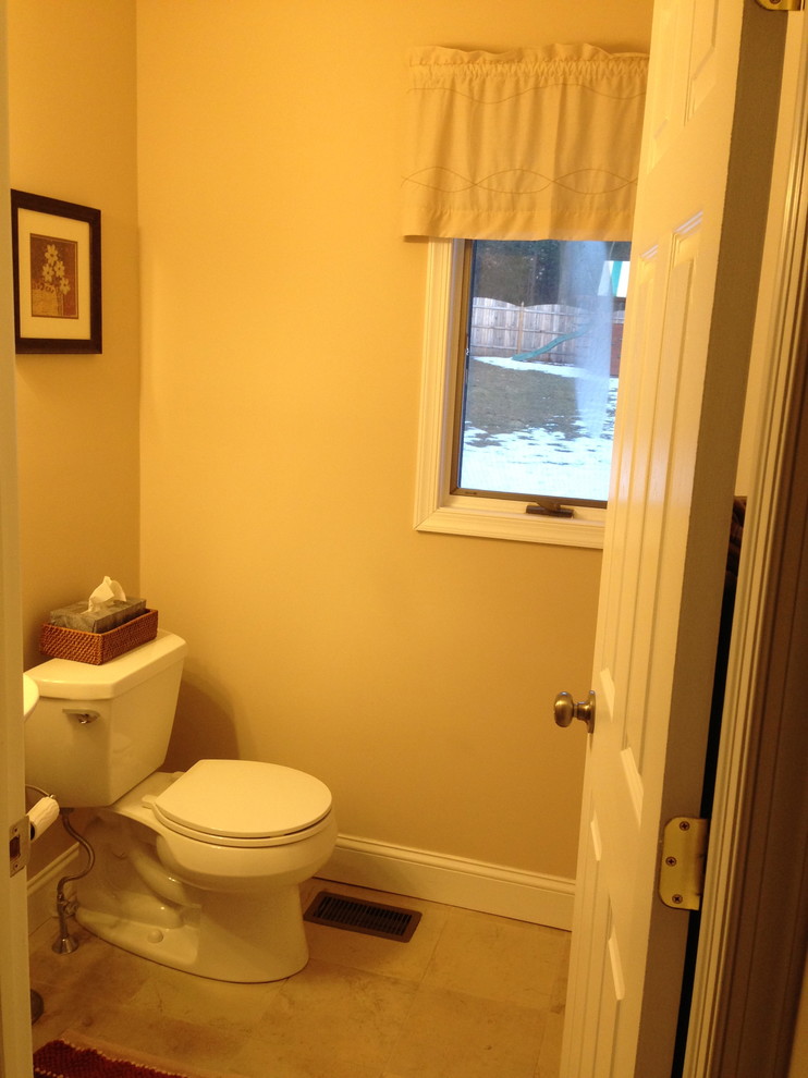 Bild på ett litet toalett, med en toalettstol med hel cisternkåpa, beige väggar och kalkstensgolv