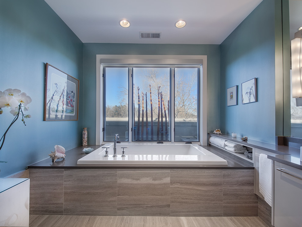 Immagine di una stanza da bagno design con vasca da incasso e pareti blu