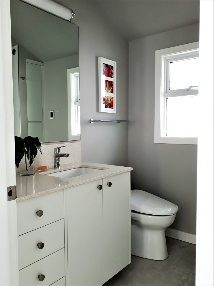 Inspiration för ett litet funkis vit vitt en-suite badrum, med släta luckor, vita skåp, ett badkar i en alkov, en dusch/badkar-kombination, en bidé, grå kakel, grå väggar, ett undermonterad handfat, bänkskiva i kvarts, dusch med duschdraperi, porslinskakel, klinkergolv i porslin och grått golv