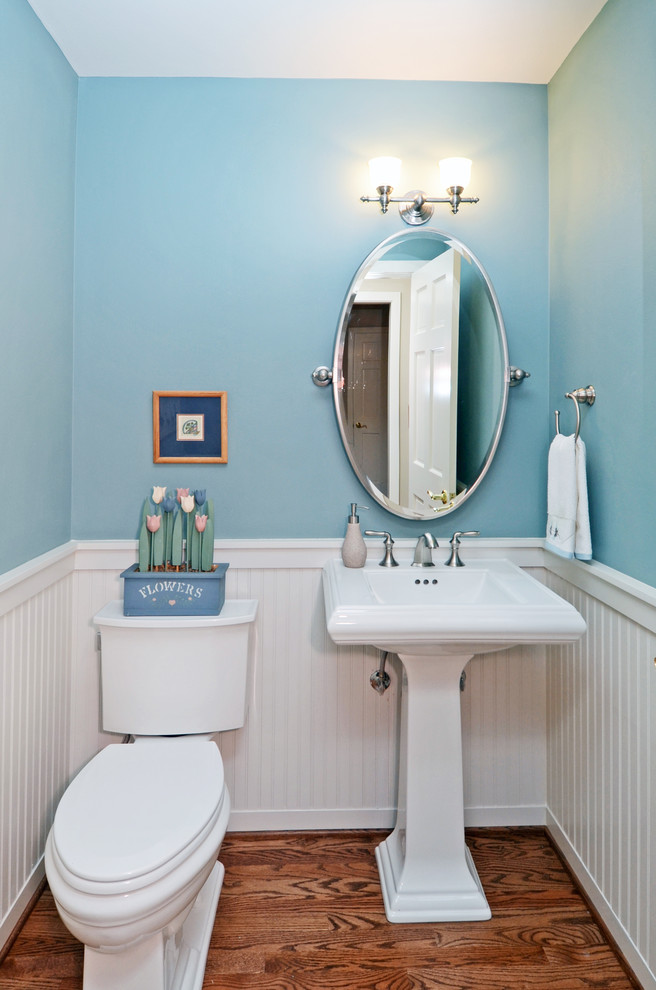 Foto de cuarto de baño clásico pequeño con sanitario de dos piezas, paredes azules, suelo de madera en tonos medios, aseo y ducha, lavabo con pedestal y suelo marrón