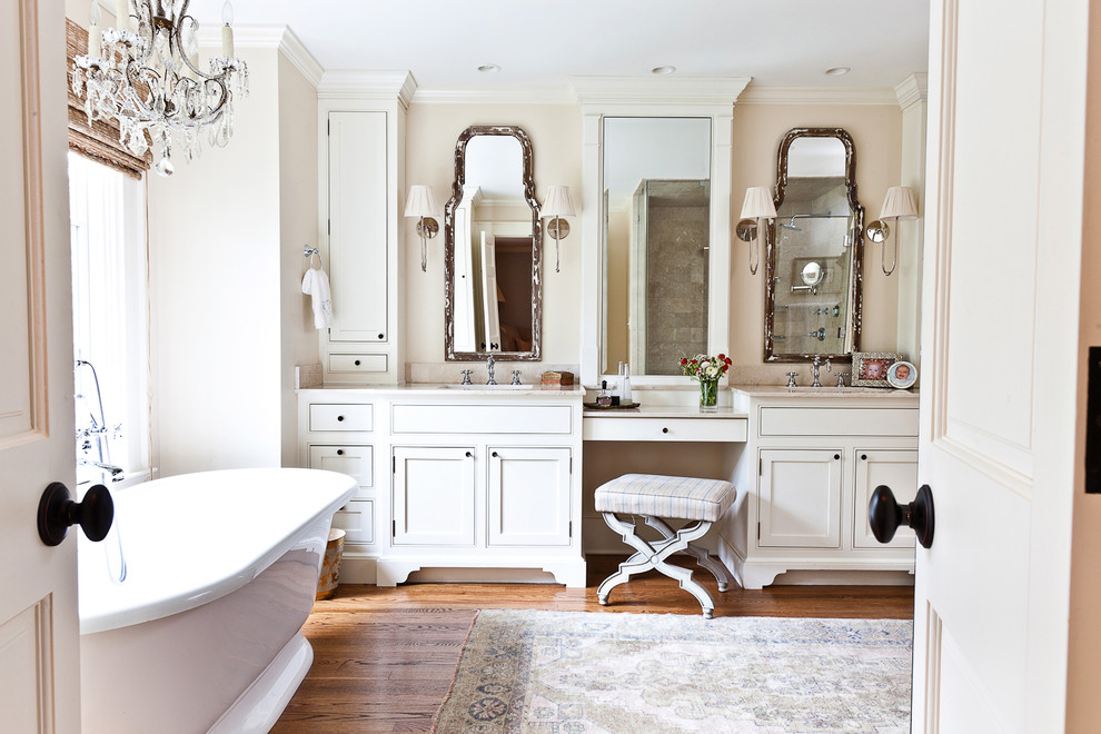 Diseño de cuarto de baño clásico con armarios con rebordes decorativos, bañera exenta y puertas de armario blancas