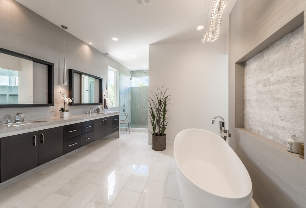 Modern inredning av ett stort en-suite badrum, med ett fristående badkar, vit kakel, vita väggar och betonggolv
