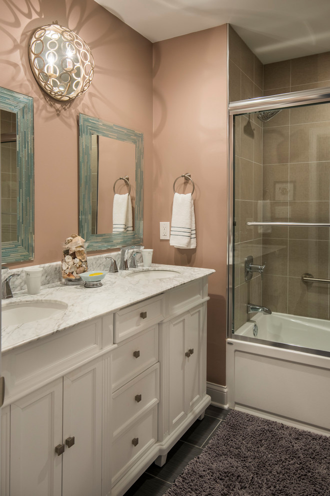 他の地域にあるお手頃価格の中くらいなトラディショナルスタイルのおしゃれな浴室 (シェーカースタイル扉のキャビネット、白いキャビネット、アルコーブ型浴槽、シャワー付き浴槽	、一体型トイレ	、茶色いタイル、ピンクの壁、アンダーカウンター洗面器、グレーの床、引戸のシャワー) の写真