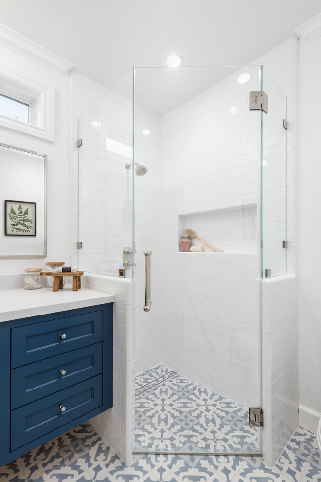 Пример оригинального дизайна: ванная комната среднего размера в стиле кантри с фасадами с декоративным кантом, синими фасадами, угловым душем, унитазом-моноблоком, белой плиткой, керамической плиткой, белыми стенами, полом из керамической плитки, душевой кабиной, врезной раковиной, столешницей из искусственного кварца, синим полом, душем с распашными дверями и белой столешницей