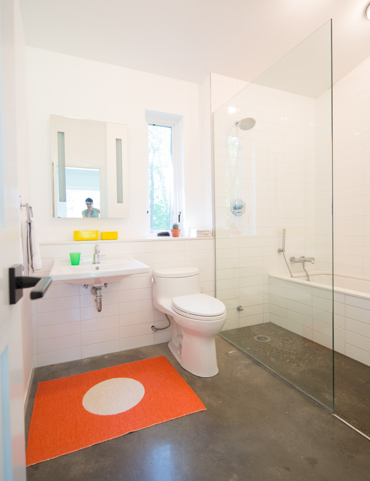 Идея дизайна: детская ванная комната среднего размера в современном стиле с полновстраиваемой ванной, душем без бортиков, унитазом-моноблоком, белой плиткой, керамогранитной плиткой, белыми стенами, бетонным полом, подвесной раковиной, серым полом и душем с распашными дверями
