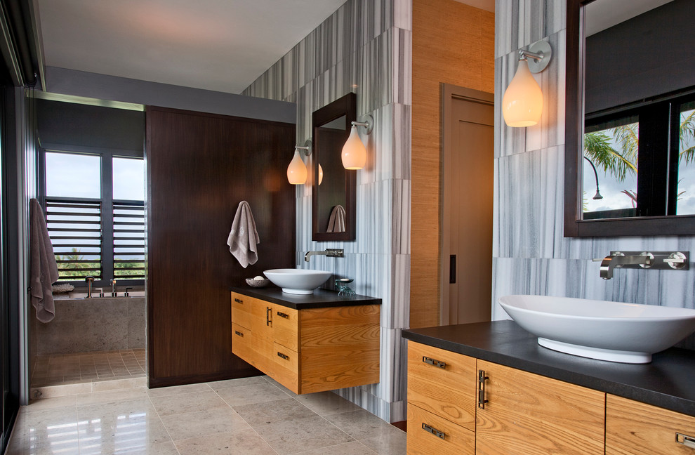 Diseño de cuarto de baño tropical con lavabo sobreencimera, armarios con paneles lisos y puertas de armario de madera clara