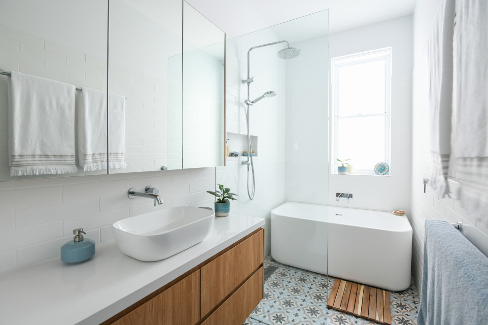 Aménagement d'une salle de bain contemporaine en bois brun avec un placard à porte plane, une baignoire indépendante, un espace douche bain, un carrelage blanc, une vasque, un sol multicolore, un plan de toilette blanc, meuble simple vasque et meuble-lavabo suspendu.