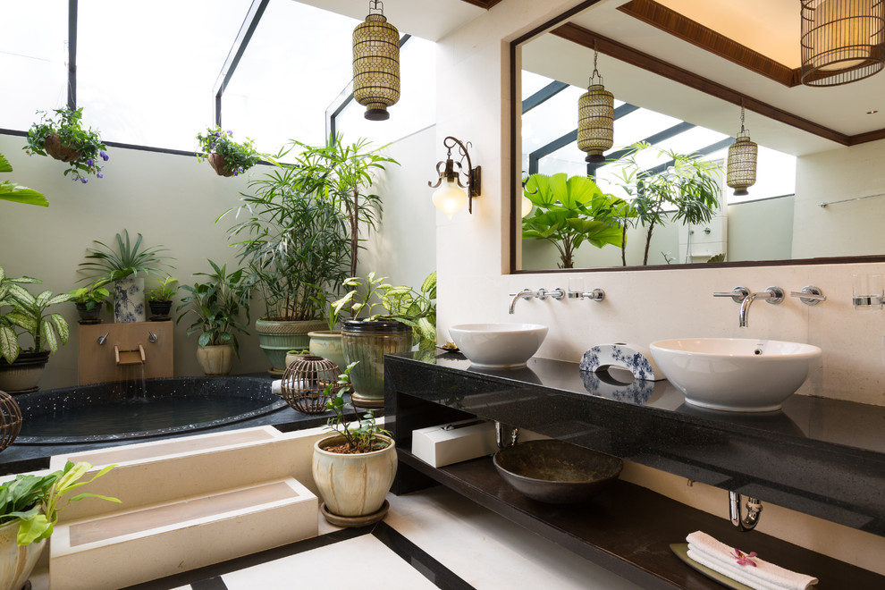 Inspiration for a tropical master drop-in bathtub remodel in Los Angeles with a vessel sink, open cabinets and beige walls