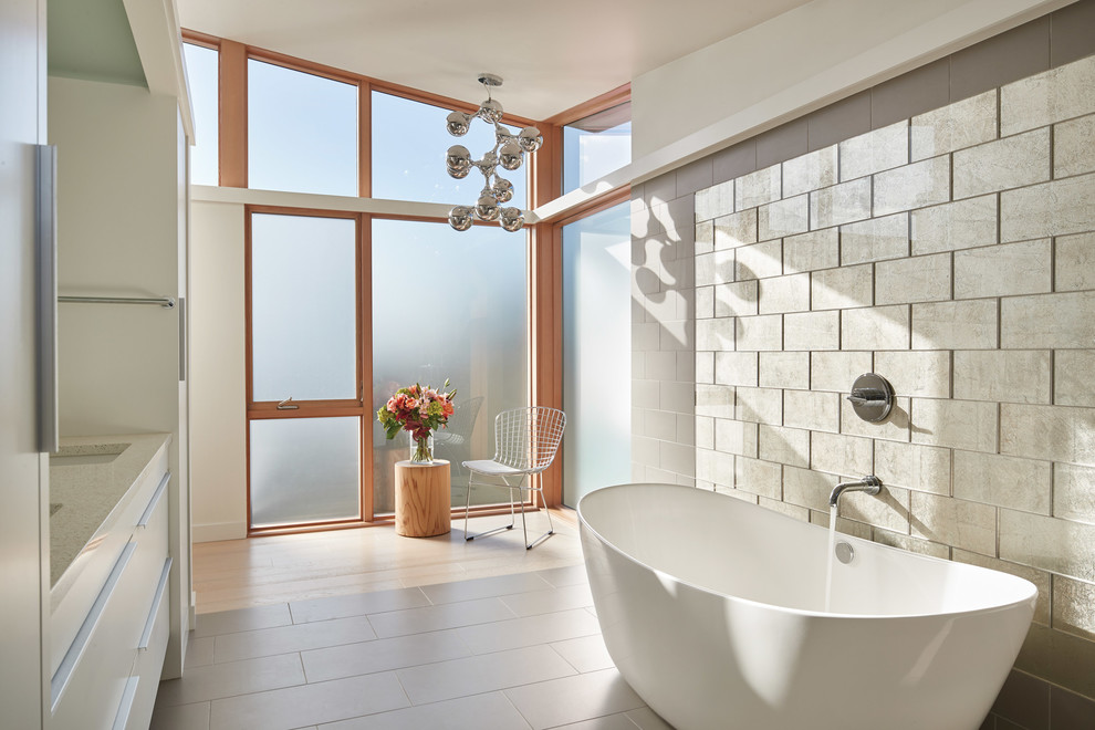 Inredning av ett modernt en-suite badrum, med släta luckor, beige skåp, ett fristående badkar, beige väggar, ett undermonterad handfat och beiget golv