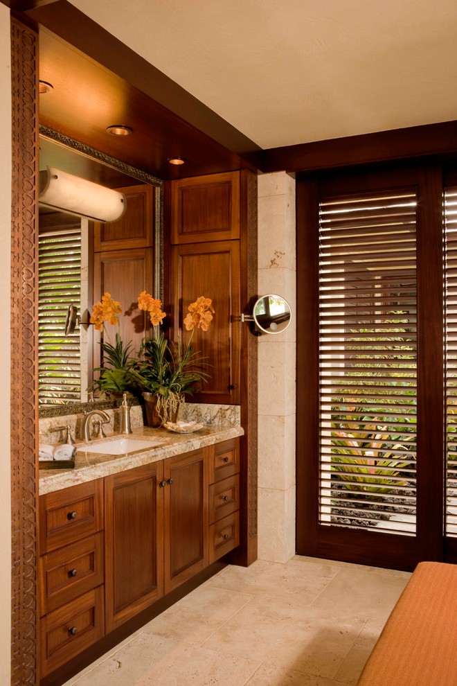 Cette photo montre une salle de bain exotique en bois foncé avec un lavabo encastré, un carrelage beige et un placard avec porte à panneau encastré.