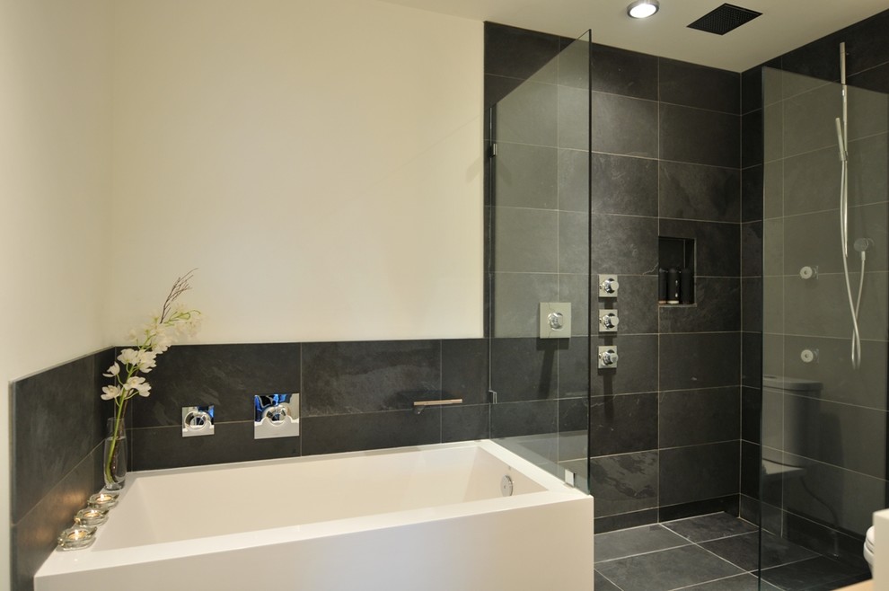 Réalisation d'une salle de bain design en bois clair de taille moyenne avec une vasque, un placard à porte plane, un plan de toilette en quartz modifié, une baignoire posée, une douche d'angle, WC séparés, un carrelage noir, un carrelage de pierre, un mur blanc et un sol en ardoise.