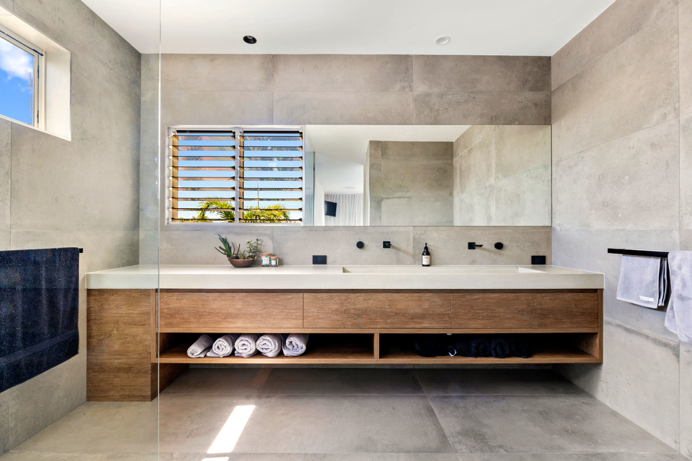 Foto de cuarto de baño actual con baldosas y/o azulejos grises, lavabo de seno grande, encimera de cemento, puertas de armario de madera oscura, paredes grises, suelo gris y encimeras grises
