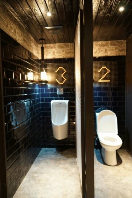 Immagine di una stanza da bagno industriale con ante in legno bruno, top piastrellato, WC a due pezzi, piastrelle nere, piastrelle in ceramica e pareti nere