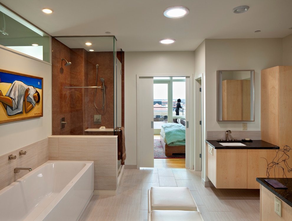 Diseño de cuarto de baño actual con armarios con paneles lisos, puertas de armario de madera clara, bañera exenta y ducha empotrada