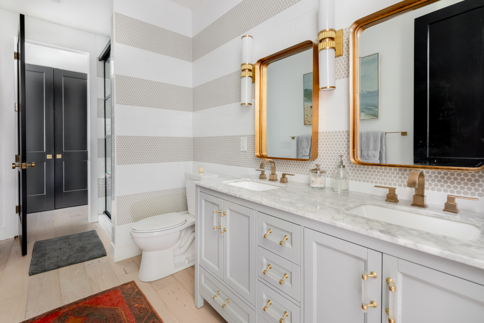 Exemple d'une grande salle de bain chic avec un placard avec porte à panneau encastré, des portes de placard grises, WC séparés, un carrelage gris, un carrelage blanc, un lavabo encastré, un sol beige, une cabine de douche à porte coulissante, un plan de toilette gris, meuble double vasque et meuble-lavabo encastré.