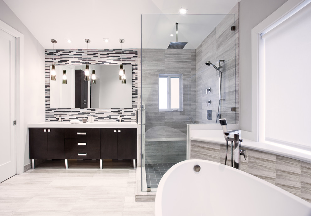 Exemple d'une salle de bain principale tendance en bois foncé de taille moyenne avec un placard à porte plane, un plan de toilette en surface solide, une baignoire indépendante, une douche d'angle, un carrelage gris, un mur gris et un sol en marbre.