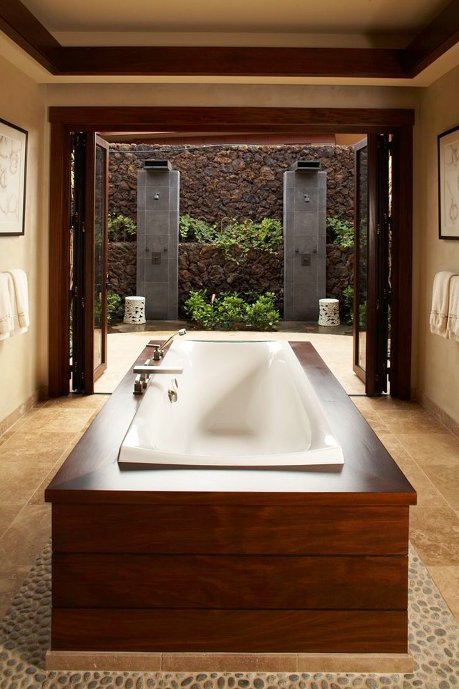 ハワイにあるトロピカルスタイルのおしゃれな浴室 (ドロップイン型浴槽、ベージュの壁) の写真