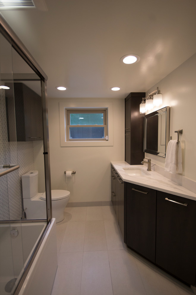 Cette image montre une petite salle de bain minimaliste en bois foncé pour enfant avec un placard à porte plane, une baignoire d'angle, un combiné douche/baignoire, WC séparés, un carrelage gris, des carreaux de céramique, un mur blanc, un sol en carrelage de céramique, un lavabo encastré et un plan de toilette en quartz modifié.