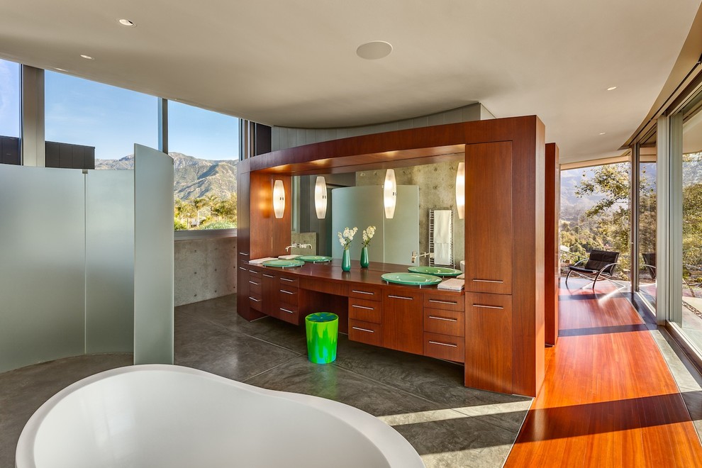 Ejemplo de cuarto de baño moderno con armarios con paneles lisos, puertas de armario de madera oscura y bañera exenta
