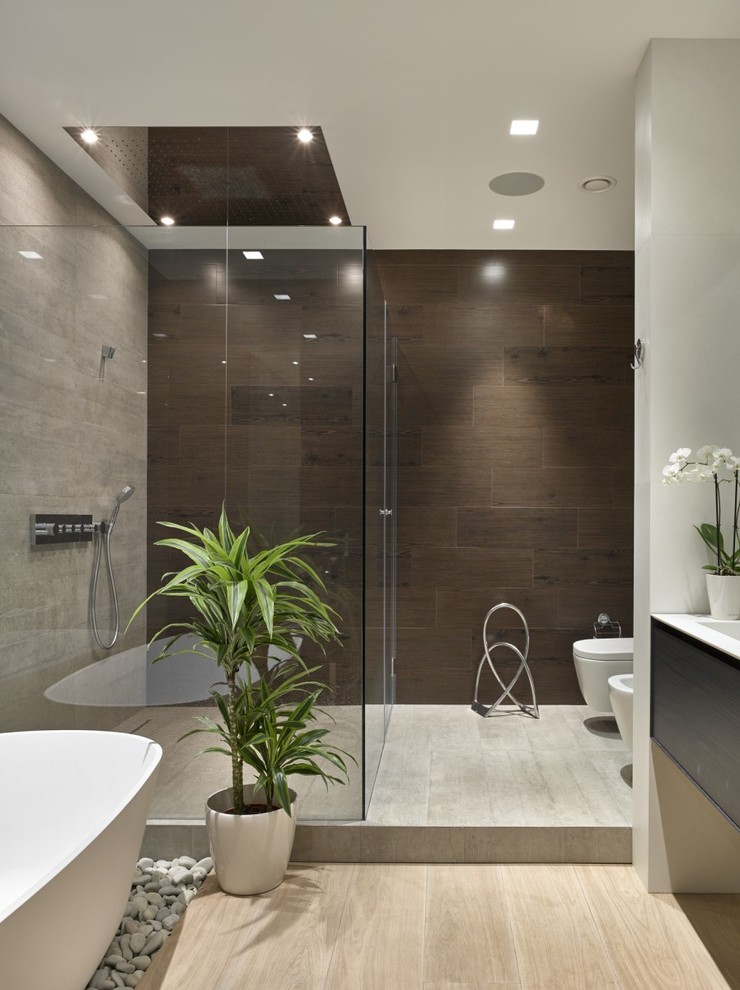 Diseño de cuarto de baño principal contemporáneo de tamaño medio con bañera exenta, armarios con paneles lisos, puertas de armario de madera en tonos medios, sanitario de pared y suelo de madera clara
