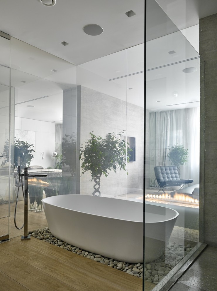 Foto de cuarto de baño principal contemporáneo de tamaño medio con bañera exenta y suelo de madera en tonos medios