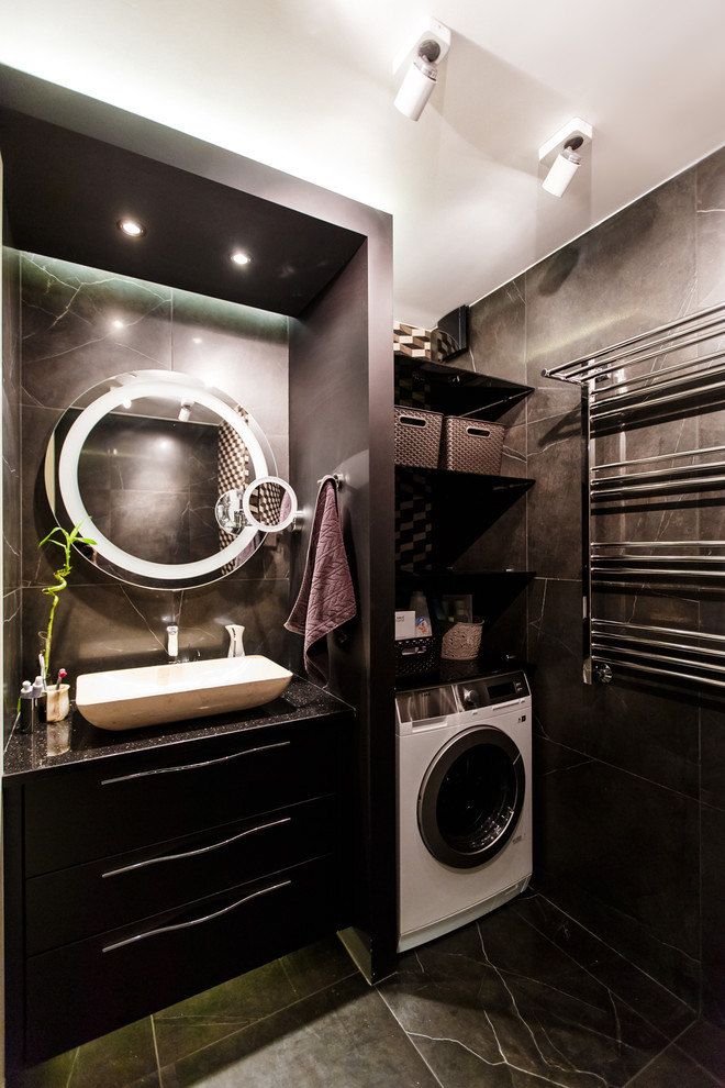 Cette image montre une salle de bain design avec des portes de placard noires, un carrelage noir et une vasque.