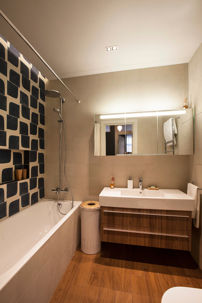 Идея дизайна: главная ванная комната в современном стиле с плоскими фасадами, фасадами цвета дерева среднего тона, накладной ванной, душем над ванной, синей плиткой, бежевой плиткой, бежевыми стенами, подвесной раковиной и зеркалом с подсветкой