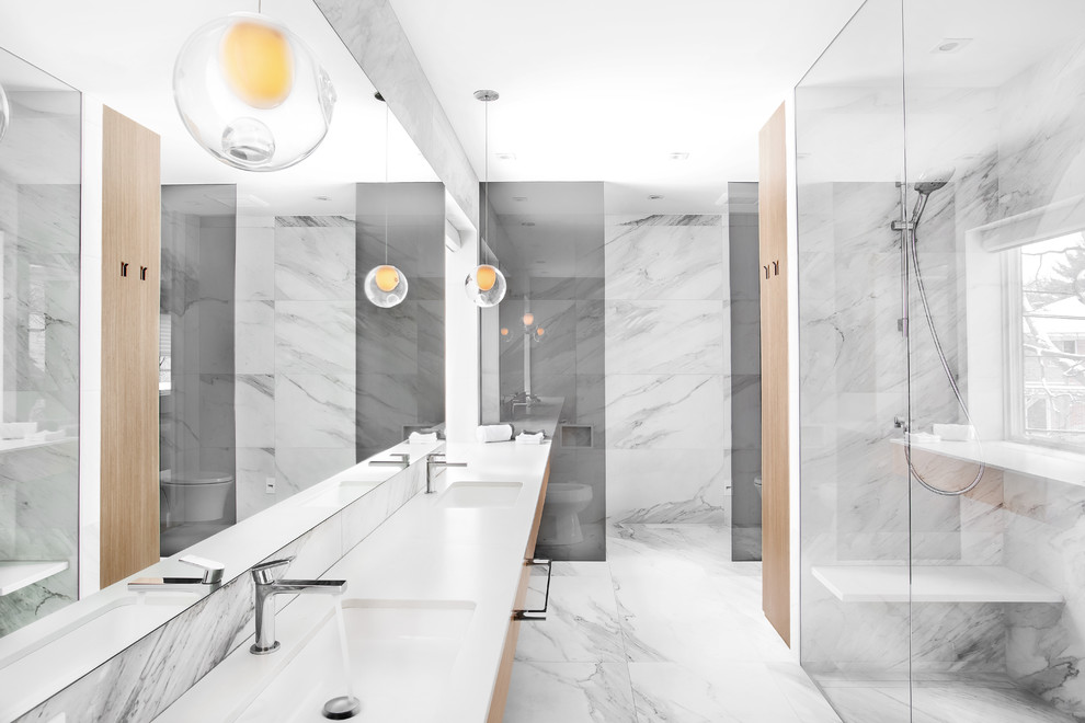 Photo of a large modern ensuite bathroom in Montreal with flat-panel cabinets, light wood cabinets, a built-in shower, a wall mounted toilet, porcelain tiles, porcelain flooring, a submerged sink and engineered stone worktops.