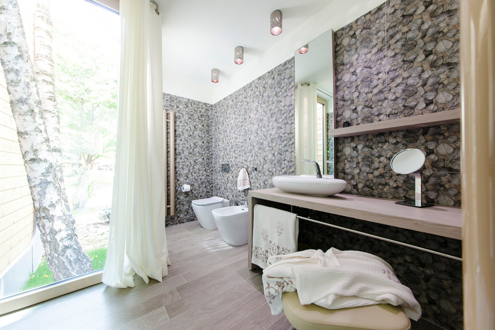 Стильный дизайн: ванная комната в современном стиле с светлыми деревянными фасадами, унитазом-моноблоком, коричневыми стенами, светлым паркетным полом, настольной раковиной и столешницей из дерева - последний тренд