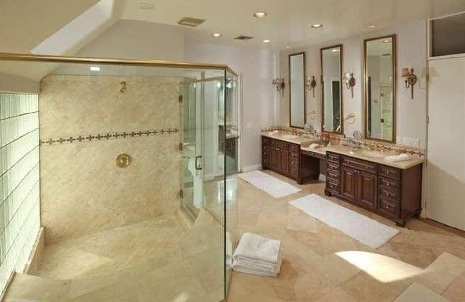 Cette photo montre une grande salle de bain principale sud-ouest américain en bois brun avec un lavabo encastré, un placard à porte shaker, une douche d'angle, un carrelage beige, des carreaux de porcelaine et un mur beige.
