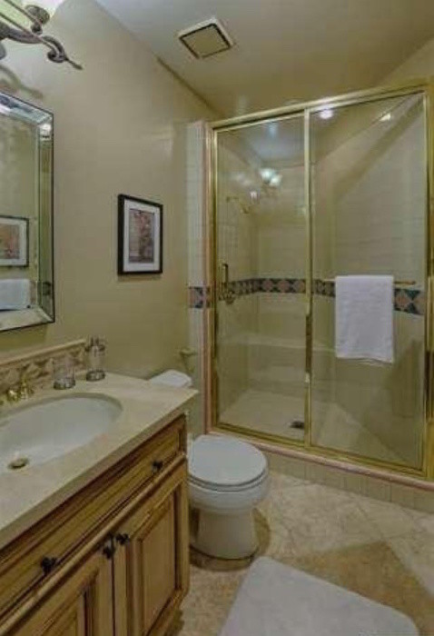 Aménagement d'une salle de bain sud-ouest américain en bois brun de taille moyenne avec un lavabo encastré, un placard à porte shaker, un carrelage beige, des carreaux de porcelaine et un mur beige.