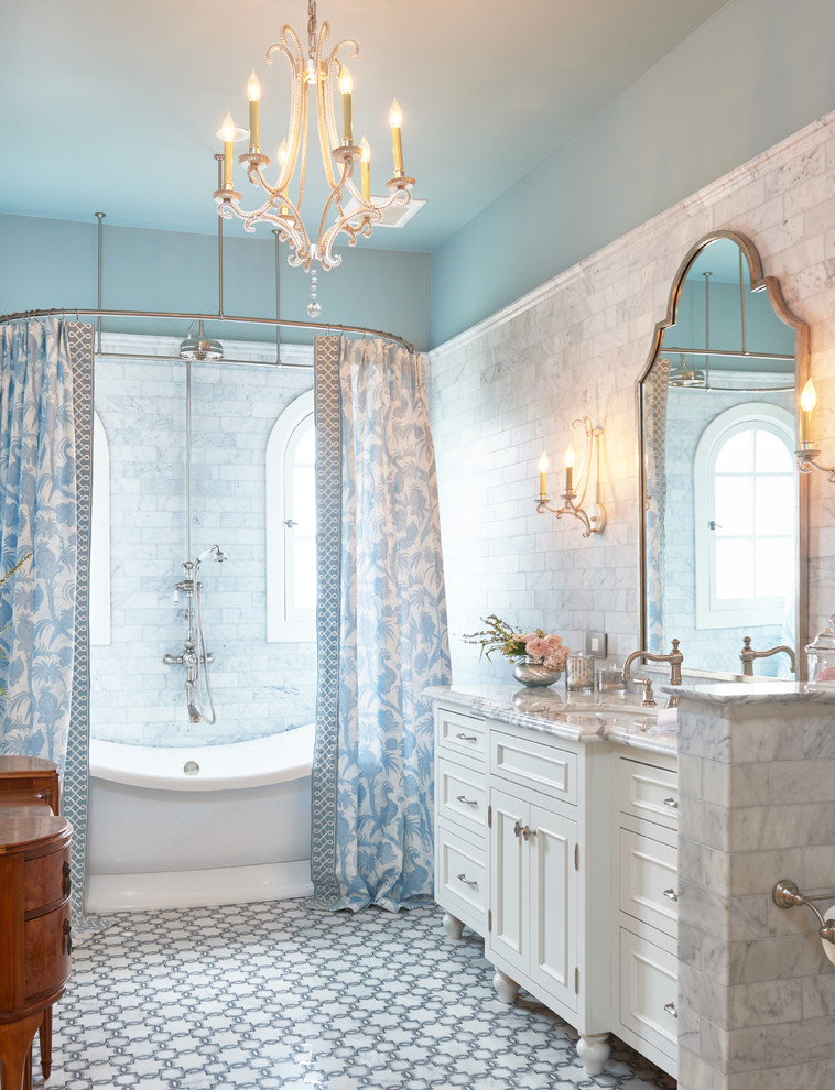 Inspiration for a classic ensuite bathroom in Los Angeles with white cabinets, a freestanding bath, grey tiles, stone tiles, blue walls, mosaic tile flooring, a submerged sink, marble worktops, a shower/bath combination, a shower curtain and recessed-panel cabinets.
