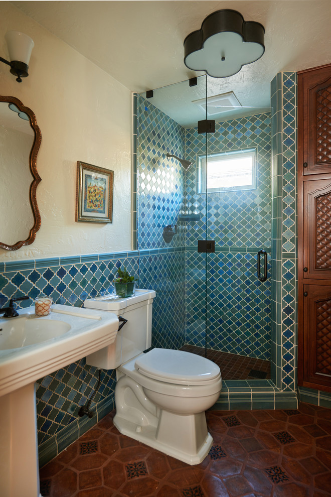 На фото: ванная комната в средиземноморском стиле с раковиной с пьедесталом, синей плиткой, угловым душем, полом из терракотовой плитки, раздельным унитазом и желтыми стенами с