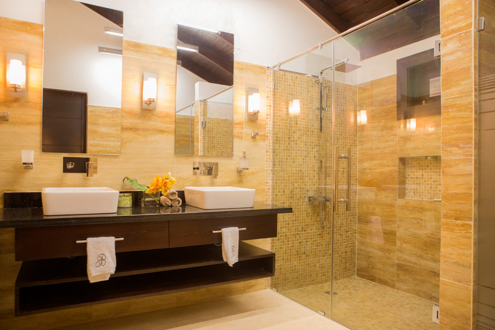 Пример оригинального дизайна: большая главная ванная комната в современном стиле с темными деревянными фасадами, ванной в нише, открытым душем, унитазом-моноблоком, бежевой плиткой, плиткой из травертина, бежевыми стенами, мраморным полом, консольной раковиной, столешницей из гранита, бежевым полом и душем с раздвижными дверями