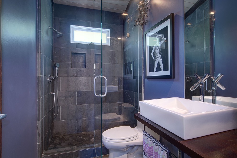 Immagine di una stanza da bagno con doccia minimal di medie dimensioni con pareti viola, nessun'anta, ante in legno scuro, doccia alcova, WC monopezzo, piastrelle grigie, piastrelle in gres porcellanato, lavabo da incasso e top in legno