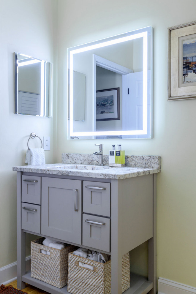 Photo of a small traditional shower room bathroom in Atlanta with shaker cabinets, grey cabinets, a built-in bath, a shower/bath combination, a one-piece toilet, white tiles, ceramic tiles, yellow walls, bamboo flooring, a submerged sink, granite worktops, brown floors, a sliding door, beige worktops, a single sink and a freestanding vanity unit.