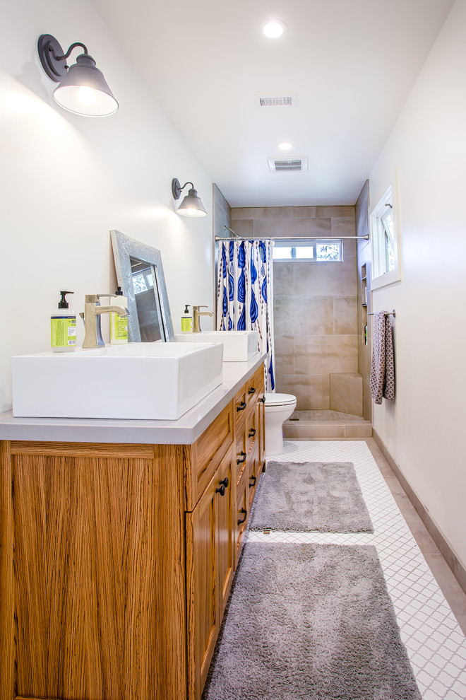 Imagen de cuarto de baño costero con lavabo sobreencimera, armarios estilo shaker, puertas de armario de madera oscura, ducha empotrada, baldosas y/o azulejos beige y paredes blancas