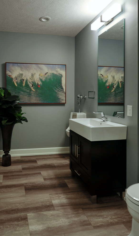 Идея дизайна: большая ванная комната в стиле ретро с плоскими фасадами, темными деревянными фасадами, писсуаром, серыми стенами, полом из керамогранита, душевой кабиной, монолитной раковиной, столешницей из искусственного камня, коричневым полом и белой столешницей