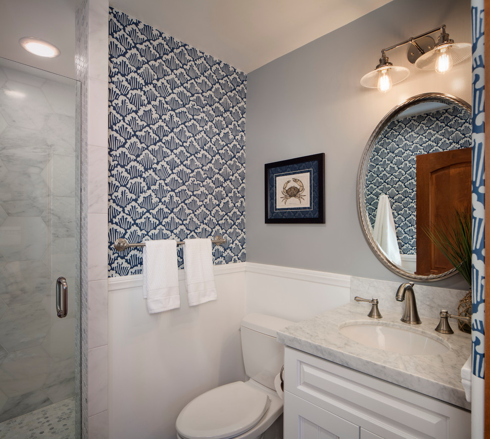 Exempel på ett litet maritimt badrum med dusch, med ett undermonterad handfat, luckor med upphöjd panel, vita skåp, marmorbänkskiva, en dusch i en alkov, en toalettstol med separat cisternkåpa, vit kakel, stenkakel och flerfärgade väggar