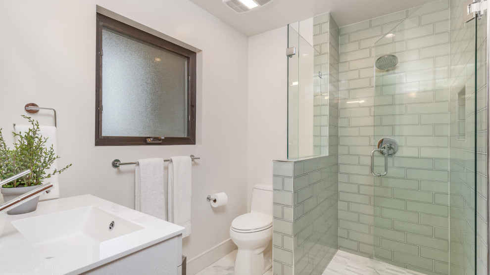 На фото: детская ванная комната среднего размера в современном стиле с плоскими фасадами, белыми фасадами, угловым душем, унитазом-моноблоком, зеленой плиткой, керамической плиткой, белыми стенами, полом из керамогранита, монолитной раковиной, столешницей из искусственного камня, серым полом, душем с распашными дверями, белой столешницей, нишей, тумбой под одну раковину и подвесной тумбой