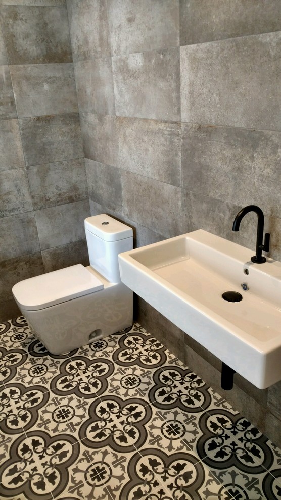 Inspiration för mellanstora industriella badrum med dusch, med en toalettstol med hel cisternkåpa, grå väggar, klinkergolv i keramik, ett väggmonterat handfat, skåp i shakerstil, skåp i slitet trä, grå kakel, cementkakel och flerfärgat golv