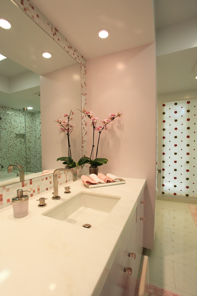 Modern inredning av ett mellanstort badrum för barn, med vita skåp, ett undermonterad handfat, rosa väggar, släta luckor, ett badkar i en alkov, en dusch i en alkov, en toalettstol med separat cisternkåpa, vit kakel, glaskakel, klinkergolv i porslin och marmorbänkskiva