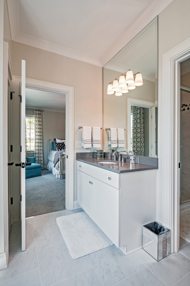 Klassisk inredning av ett mellanstort badrum med dusch, med skåp i shakerstil, vita skåp, beige väggar, marmorgolv, ett undermonterad handfat, bänkskiva i akrylsten och grått golv