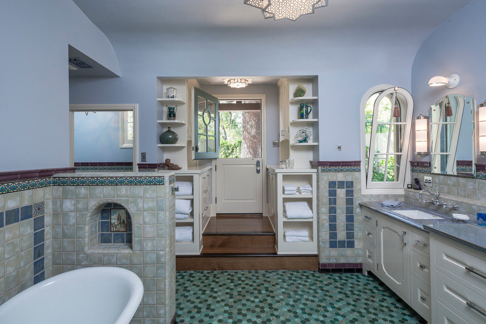 Beach style ensuite bathroom in Los Angeles with recessed-panel cabinets, white cabinets, a freestanding bath, a one-piece toilet, blue tiles, ceramic tiles, blue walls, mosaic tile flooring, a submerged sink and zinc worktops.