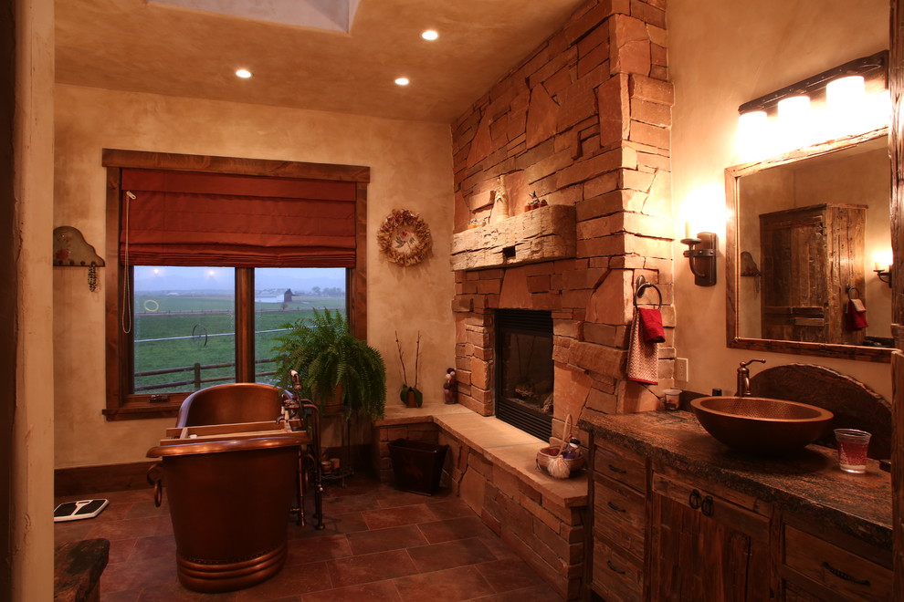 Inredning av ett rustikt stort en-suite badrum, med ett fristående handfat, släta luckor, skåp i slitet trä, granitbänkskiva, ett fristående badkar, stenkakel, beige väggar och brun kakel