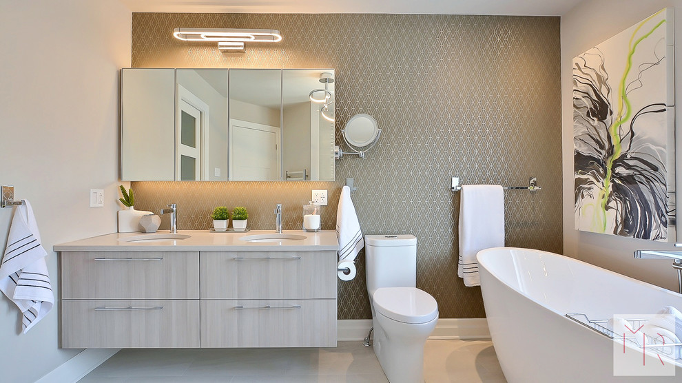 Inspiration for a medium sized modern ensuite bathroom in Montreal with flat-panel cabinets, grey cabinets, a freestanding bath, a double shower, a one-piece toilet, grey tiles, ceramic tiles, grey walls, ceramic flooring, a submerged sink, engineered stone worktops, grey floors and an open shower.