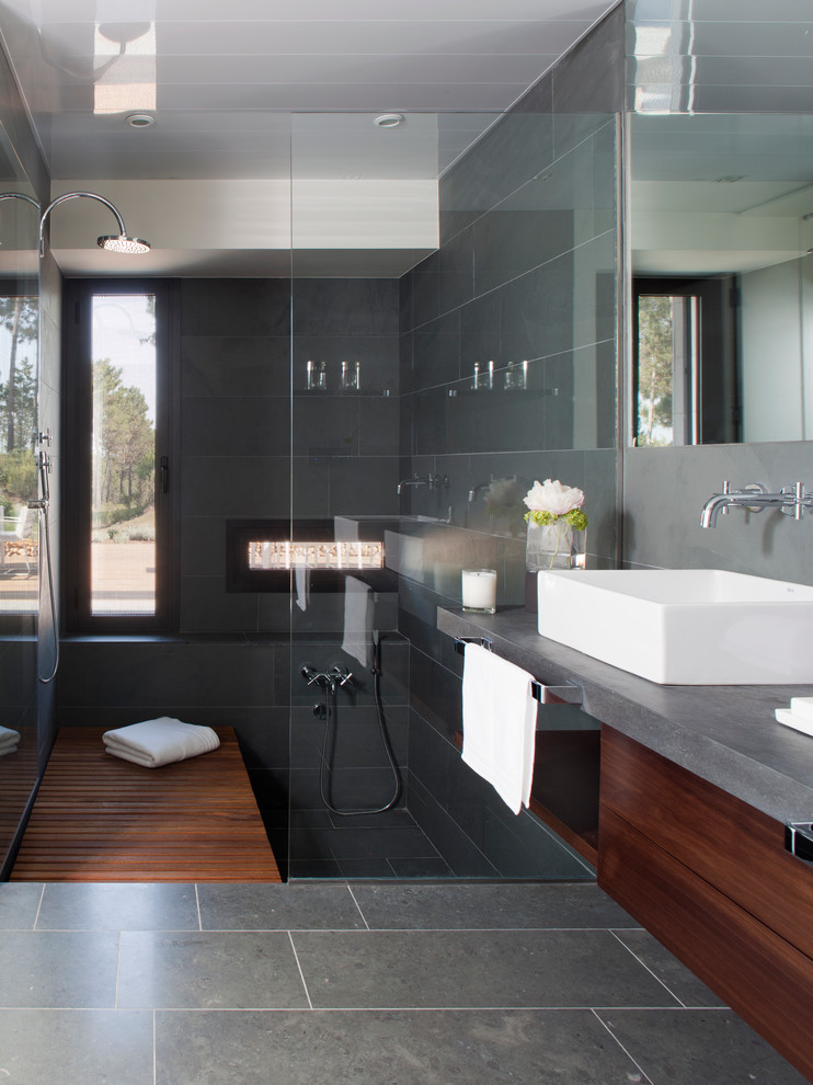 Aménagement d'une grande salle de bain contemporaine en bois brun avec un placard à porte plane, un carrelage gris, des carreaux de céramique, un mur gris, un sol en carrelage de céramique, une vasque et un plan de toilette en béton.