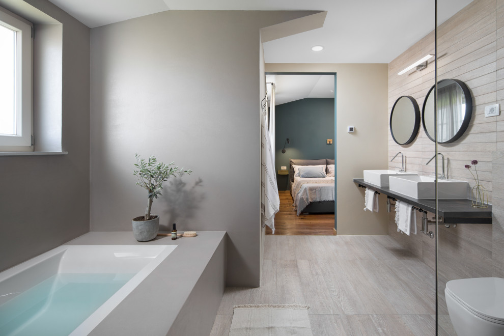 Foto di una grande stanza da bagno padronale mediterranea con ante beige, pareti beige, top nero, due lavabi, vasca da incasso, pavimento con piastrelle effetto legno, lavabo a bacinella e pavimento grigio
