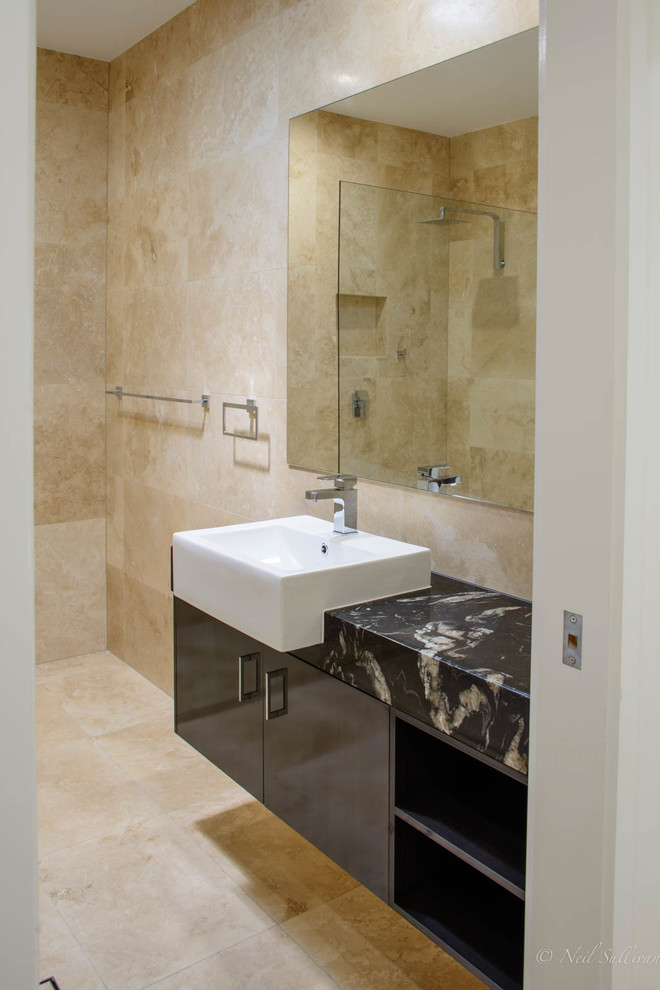 Medium sized nautical ensuite bathroom in Sunshine Coast with porcelain flooring, marble worktops, flat-panel cabinets, black cabinets, a freestanding bath, an alcove shower, travertine tiles, an integrated sink, beige floors and an open shower.